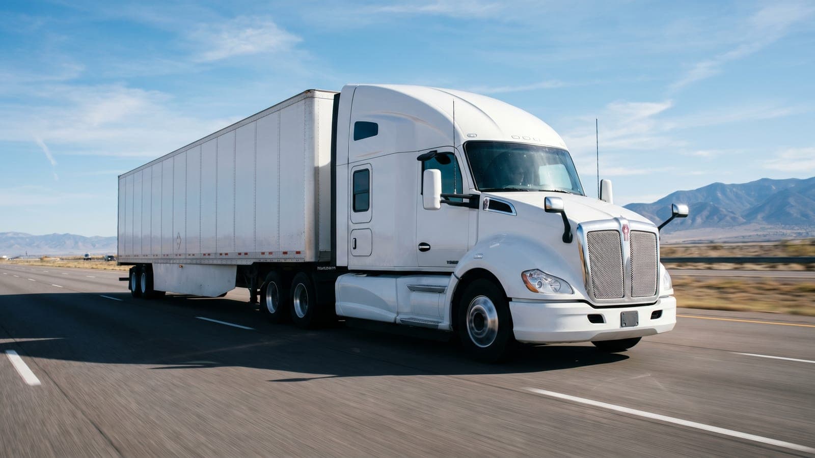 White Class-8 semi-truck with dry-van trailer on a US interstate